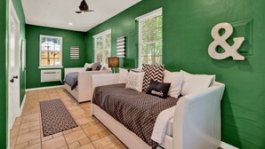 Una habitación con dos sofás blancos, un tapete estampado y una pared verde con un gran símbolo de 'y'.