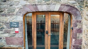 A stone building with a wooden door and a sign that reads "The Forge". - St Davids Hideaway with Roll-top Bath & Log Burner (St Davids)