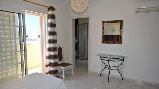 Habitación de hotel con cama, una silla, una mesa, un espejo y vistas al exterior.