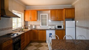 Una cocina con armarios de madera, estufa a gas, microondas, lavavajillas y refrigerador.