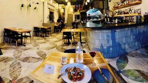 Ein Restaurant mit Barbereich, Tischen, Stühlen und einem gemusterten Boden.