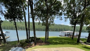Une terrasse extérieure équipée d’un barbecue, d’un foyer et d’un espace salon, le tout avec vue sur un lac.