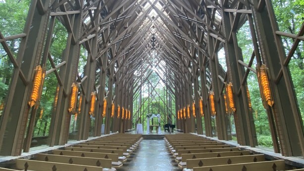 L’intérieur d’une église, avec un plafond voûté élevé, des bancs disposés en rangées et un sol en pierre.