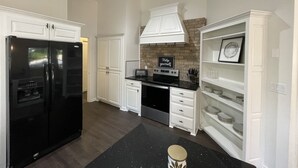 Une cuisine moderne avec des meubles blancs, un réfrigérateur noir et un four encastré.