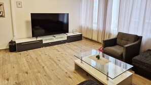 Una sala de estar moderna con un televisor de pantalla plana, una mesa de centro de vidrio y un sofá cómodo.