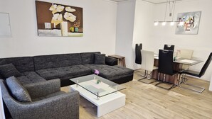 Una sala de estar moderna con un sofá modular, una mesa de centro de vidrio y un comedor con mesa y sillas.
