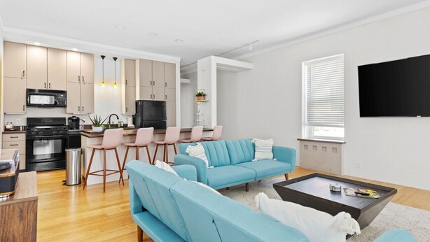 A modern living room with a sofa set, a coffee table, and a TV mounted on the wall.