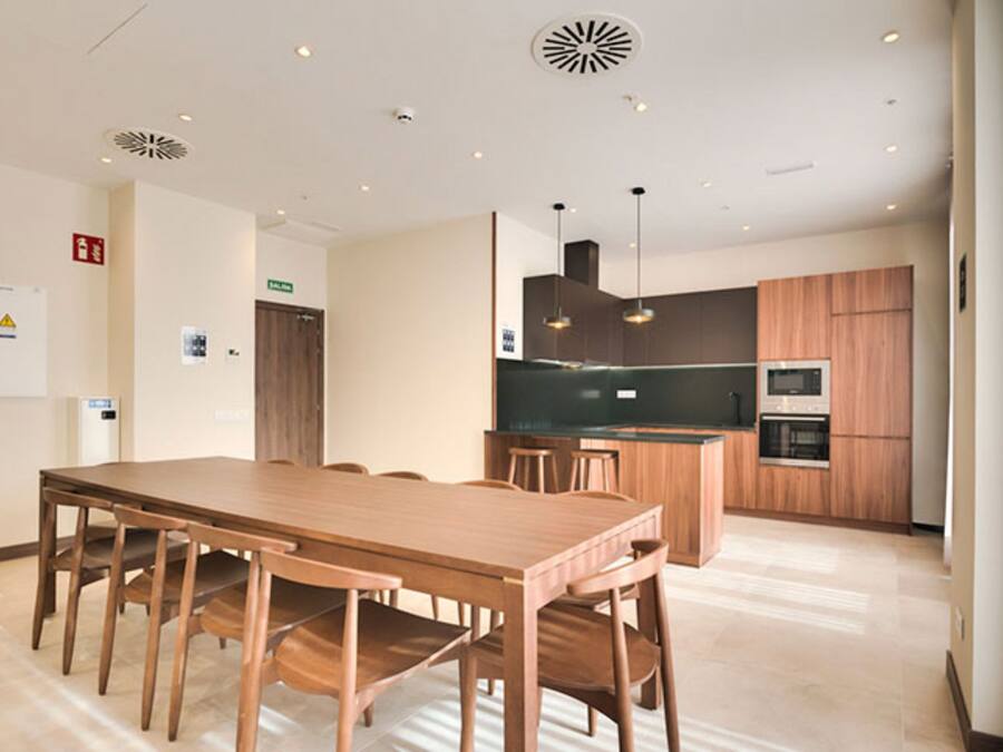 Una cocina moderna con armarios de madera, una isla central con taburetes y electrodomésticos integrados.
