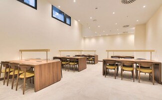 Una sala conferenze con diversi tavoli e sedie, dotata di computer portatili e schermi, in un ambiente moderno con illuminazione a incasso.