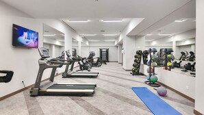 Une salle de sport moderne équipée de tapis de course, de vélos d’exercice et d’une variété d’haltères et de ballons.