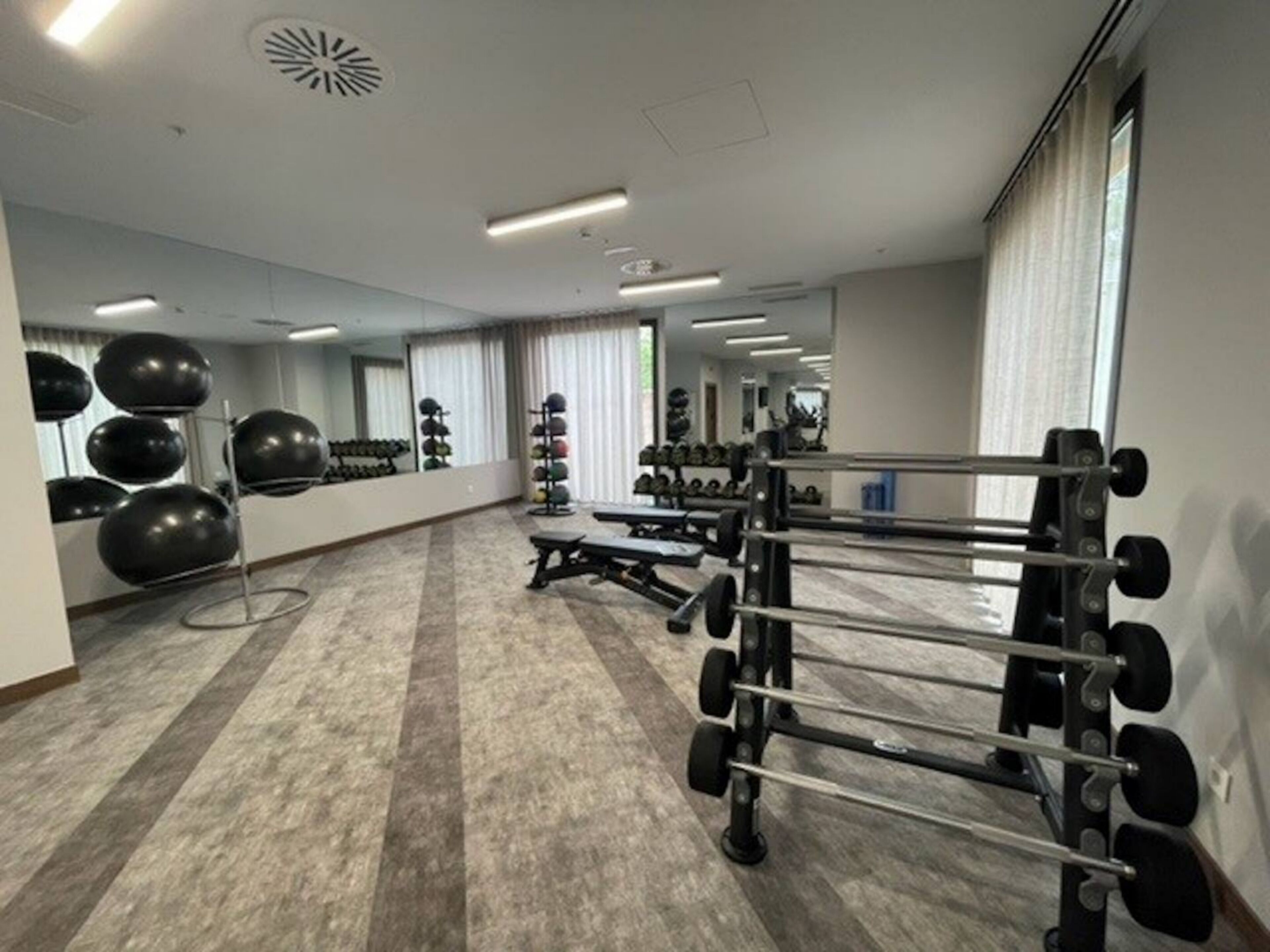 A gym with exercise equipment, a mirror, and a carpeted floor.