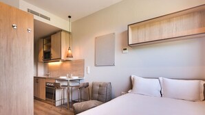 Une chambre d’hôtel comprenant un lit, un bureau avec une chaise, un four à micro-ondes et une petite kitchenette.