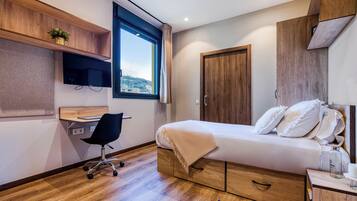 Une chambre moderne avec un lit, un bureau, une chaise et une fenêtre.