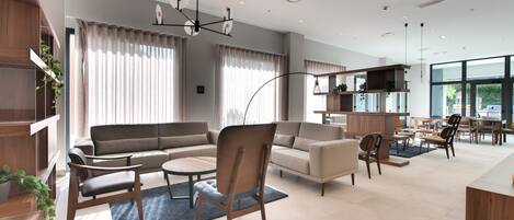 A modern living room with a sofa, armchairs, a coffee table, and a dining area with chairs and a table.