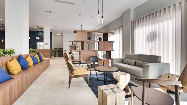 Un salon moderne comprenant un canapé, des fauteuils, une table basse et une bibliothèque en bois.