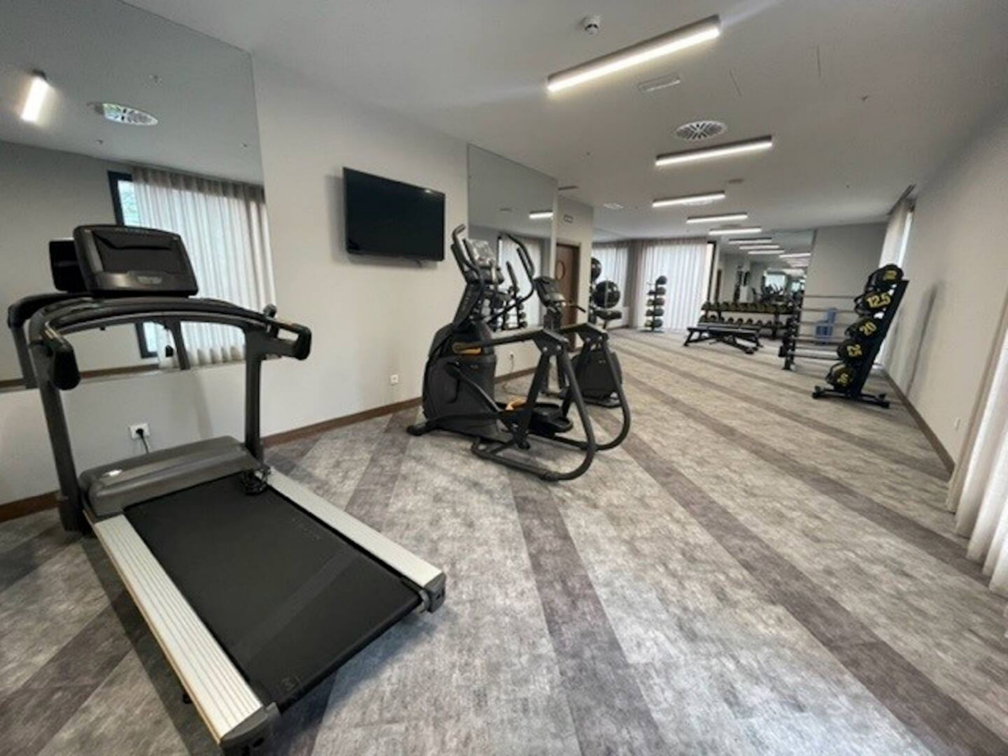 Een sportschool met loopbanden, elliptische trainers en gewichten.