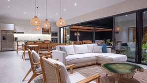 A modern living room with a sectional sofa, wooden chairs, and a dining area. - Casa Zuri Luxury Villa + Guest House & Beach Club (Tamarindo)