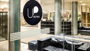 En moderne hotellobby med receptionsdisk, læderpolstrede møbler og en stenvæg.