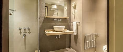 Un baño moderno con ducha de vidrio, un espejo grande, un lavabo y un inodoro.