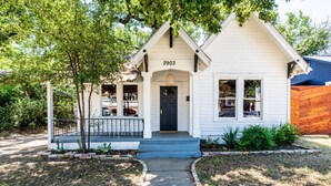 A white house with the number 2903, a front porch, and a small garden.