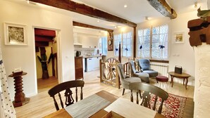 Un intérieur chaleureux comprenant un coin repas, une cuisine et un espace de vie avec une grande fenêtre.