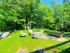 An outdoor seating area with a table and chairs, surrounded by lush greenery and trees.