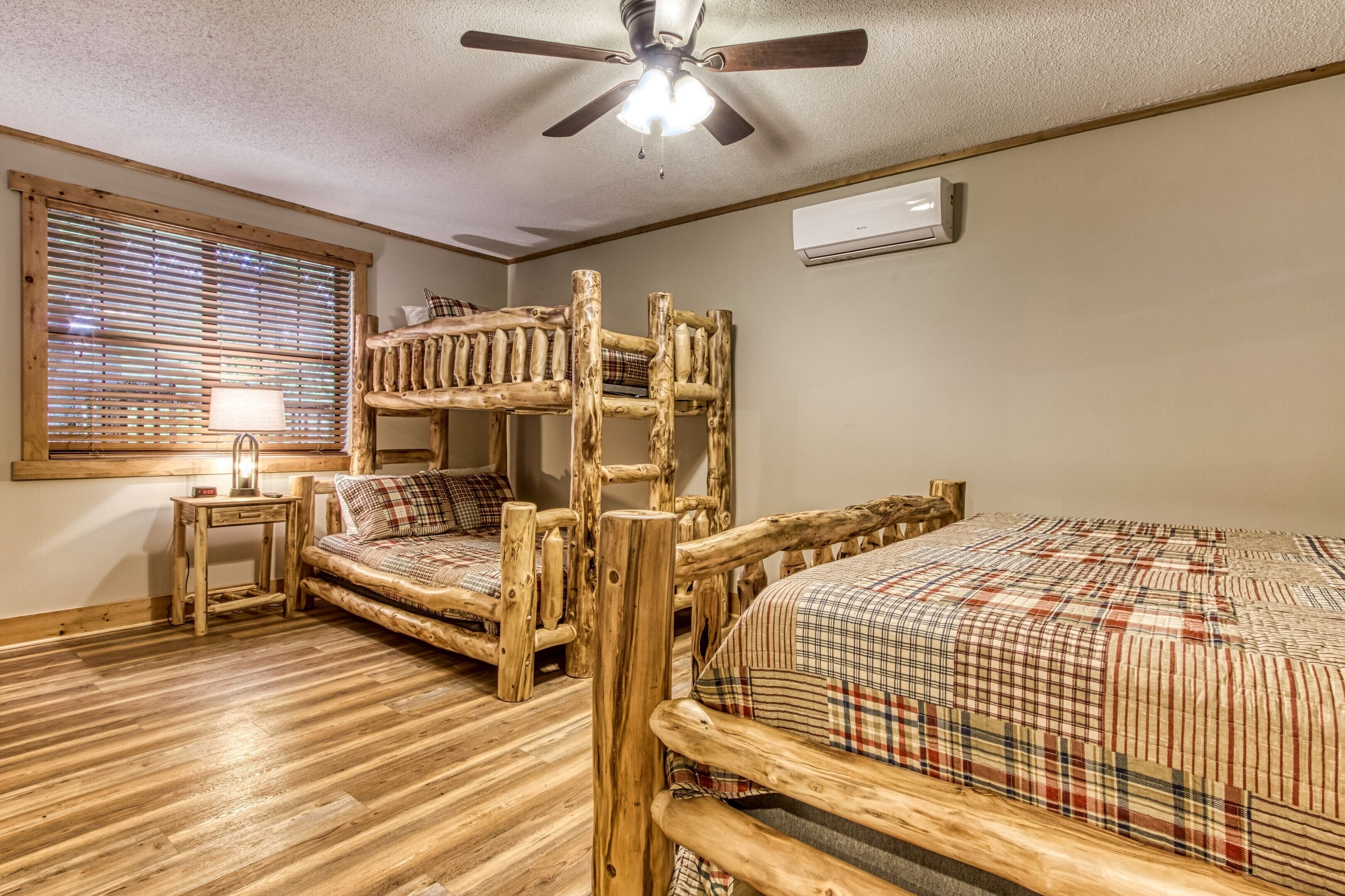 A room with a bunk bed, a desk, a lamp, and a ceiling fan.
