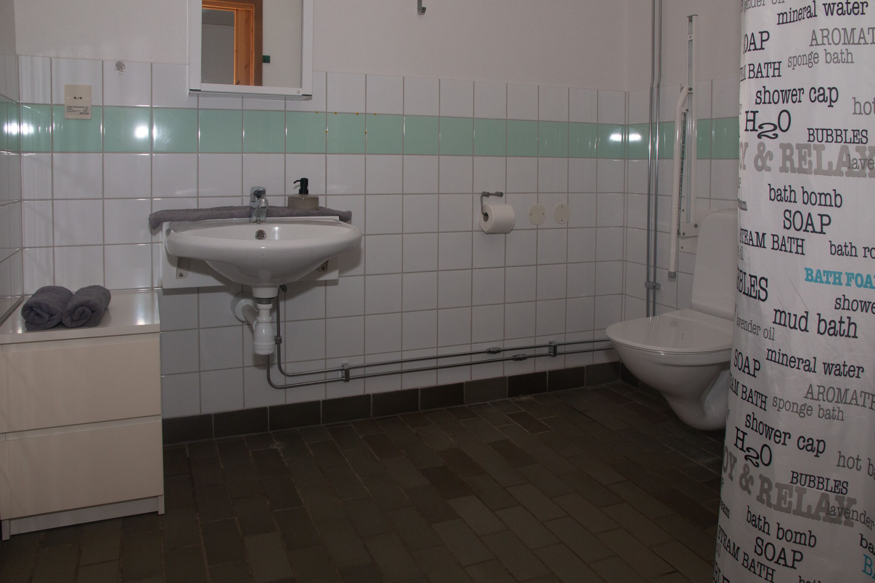 Uma casa de banho com lavatório, sanita e um porta-toalhas.