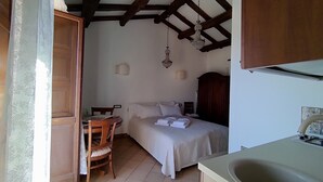 Un dormitorio pequeño y acogedor con una cama, una silla de madera, un escritorio y una lámpara colgante.