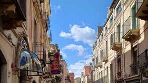 Una calle adoquinada flanqueada por edificios históricos, con balcones y escaparates.