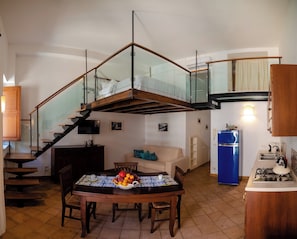 A modern kitchen with a blue refrigerator, wooden dining table, and a staircase with glass railings. - Porta Messina Apartment/Vilagos Apartments & Loft Taormina (Taormina)