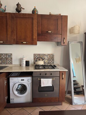 Una cocina con armarios de madera, lavadora, estufa y espejo.