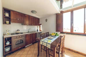 A kitchen with wooden cabinets, a dining table with chairs, and a window with a view.