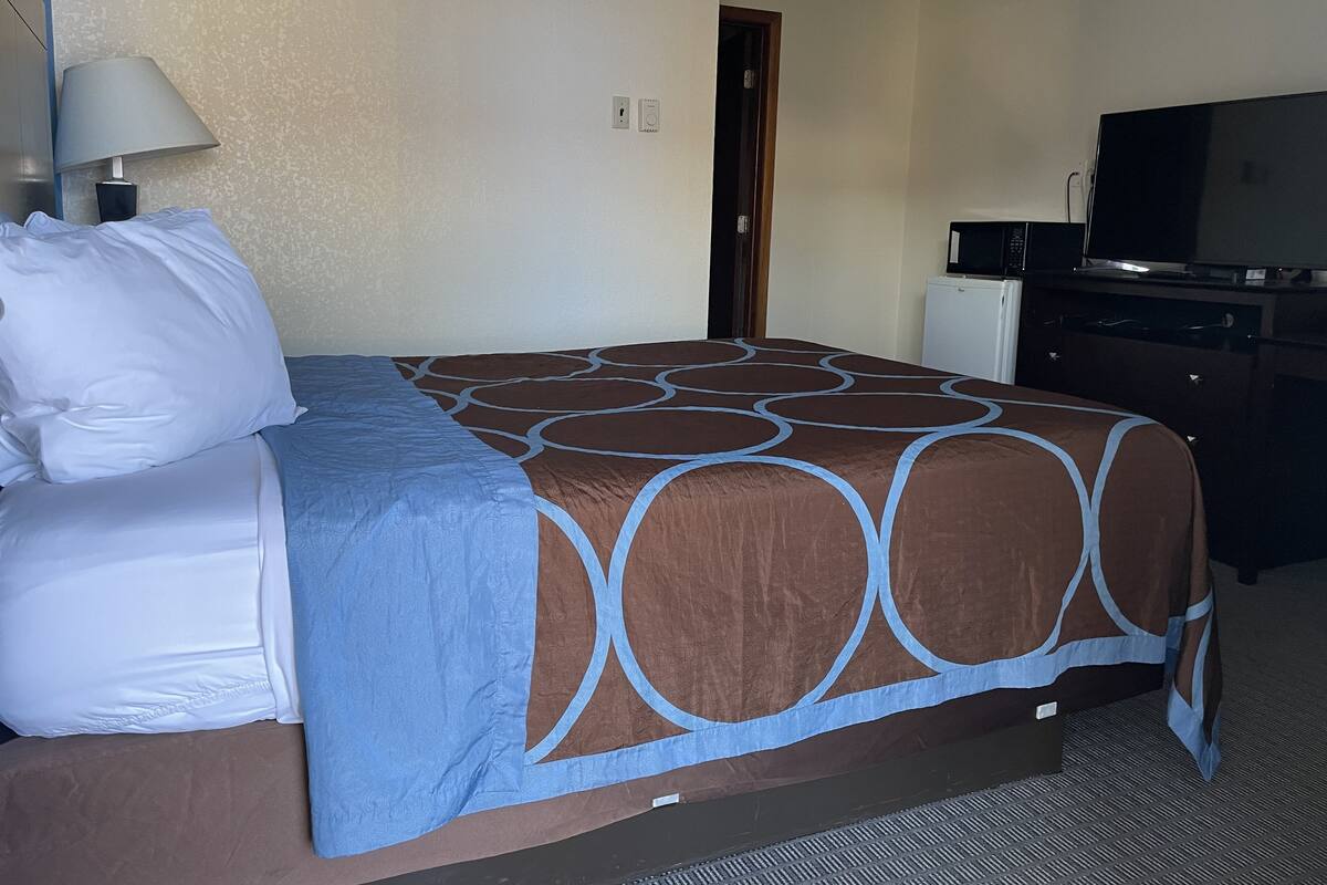 A hotel room with a bed, a desk with a computer, a television, and a door.