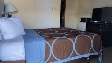 Ein Hotelzimmer mit einem Bett, einem Schreibtisch mit Computer, einem Fernseher und einer Tür.