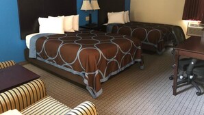 A hotel room with two beds, a sofa, a desk, and a lamp. - AmeriVu Inn & Suites (Eau Claire)