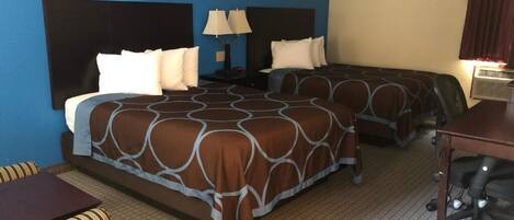 A hotel room with two beds, a sofa, a desk, and a lamp.