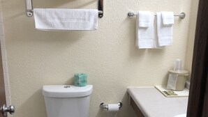 A bathroom with a toilet, a sink, and a towel rack. - AmeriVu Inn & Suites (Eau Claire)