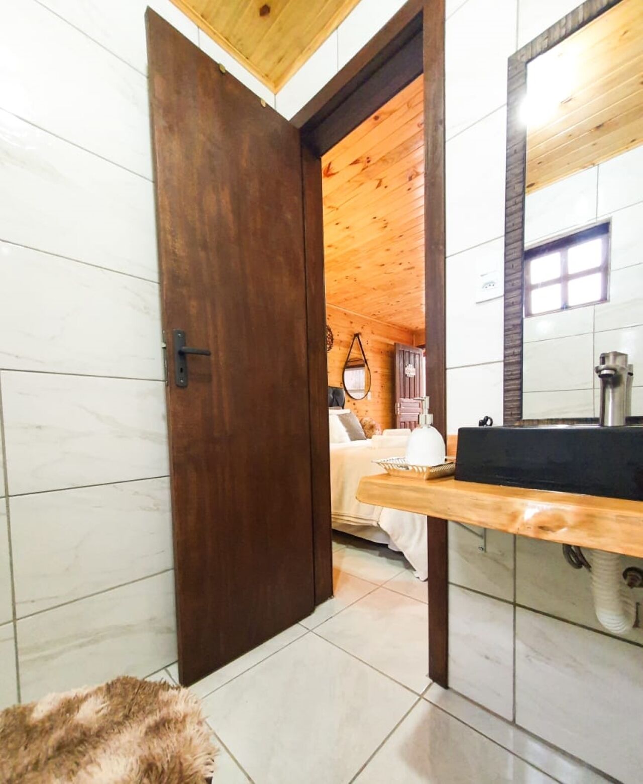 Ein Badezimmer mit Holztür, Waschbecken und Spiegel.