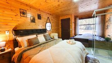 Relax in a serene bedroom with a large bed, featuring a quilted duvet and multiple pillows, and a glass door leading to an outdoor area.