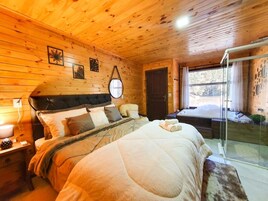 Un dormitorio rústico de madera con cama, mesita de noche y puerta de cristal que da a un balcón.