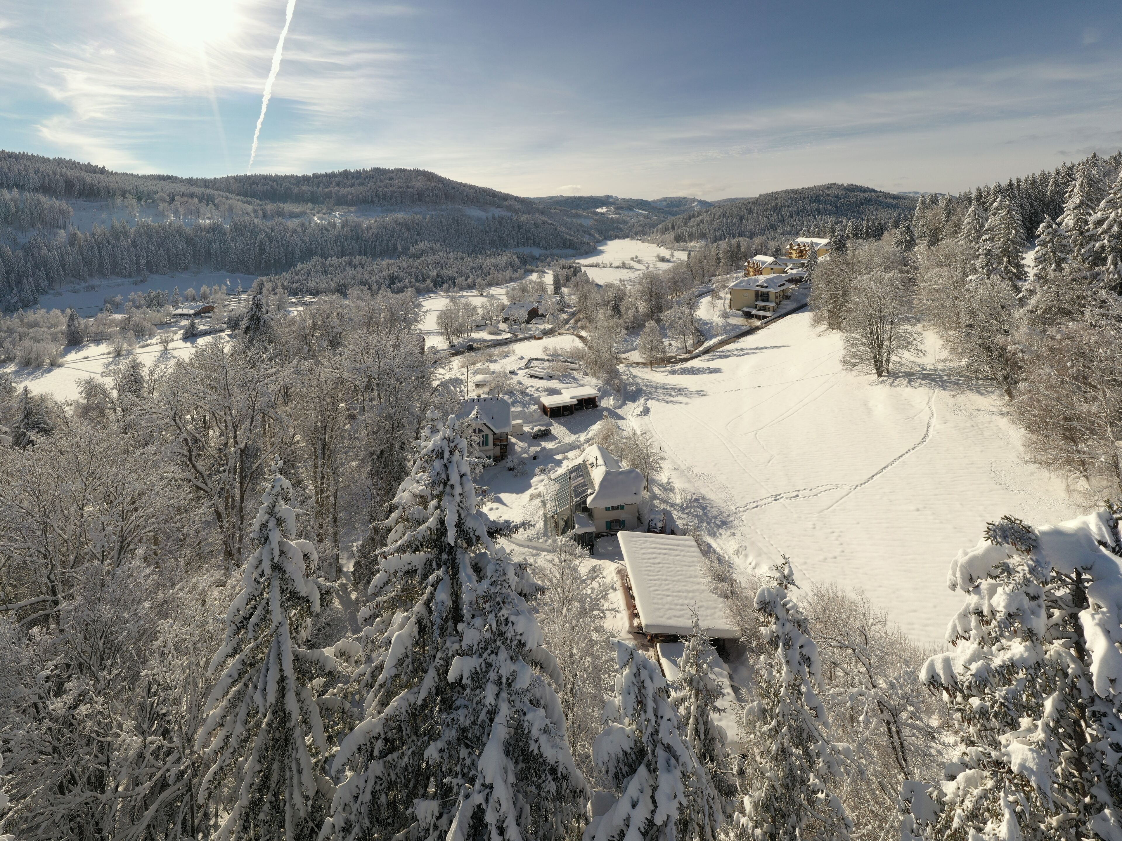 Schneebedeckte Landschaft mit einer Hütte und einer Skipiste.