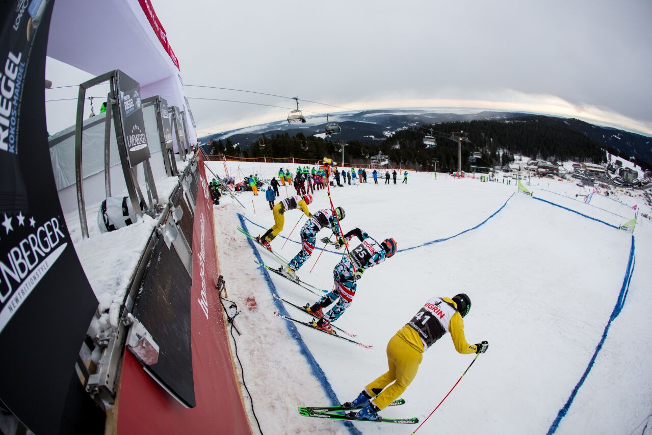 Une piste de ski avec des skieurs en compétition, un télésiège et un paysage montagneux en arrière-plan.