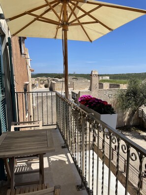 A balcony with a table and chairs, a wooden umbrella, and a flower planter. - Antoine (Bonifacio)