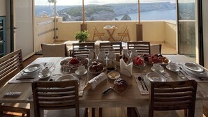 A dining table set with breakfast items, a chandelier, and a view of cliffs and water. - Antoine (Bonifacio)