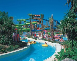 Ein Wasserpark mit zahlreichen Rutschen und Pools, umgeben von Palmen und tropischer Bepflanzung.