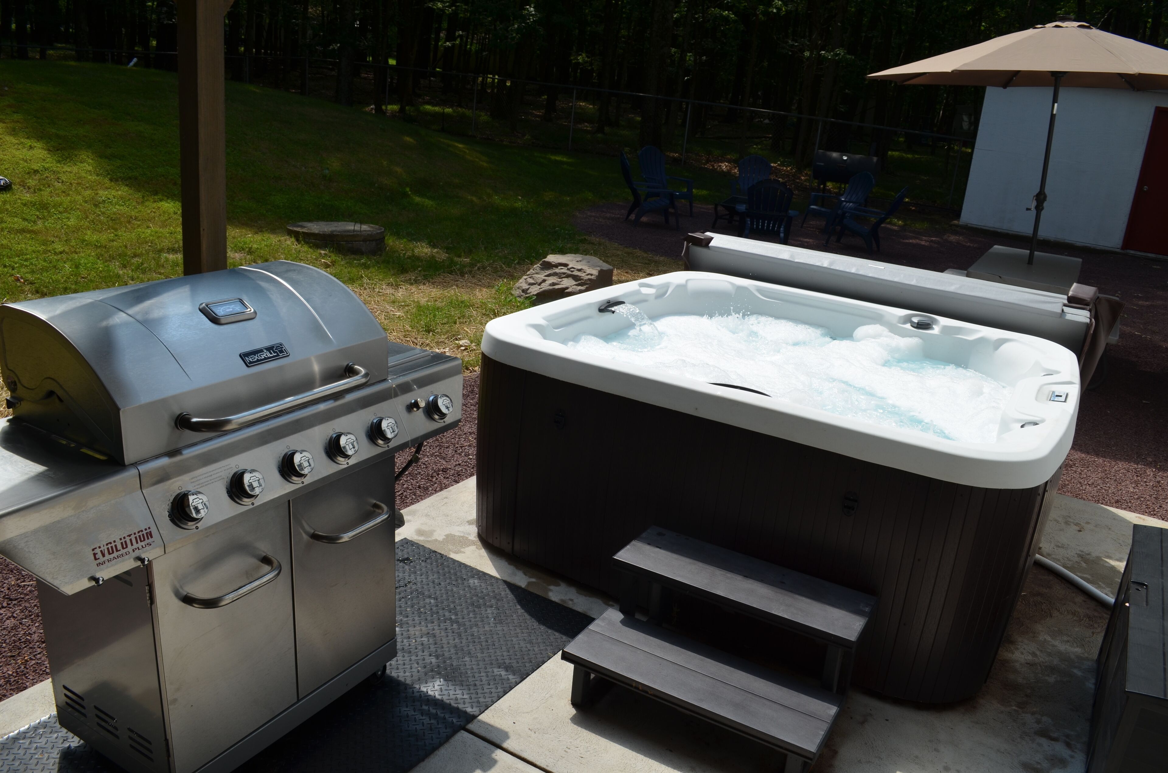 A barbecue grill and hot tub set up outdoors.