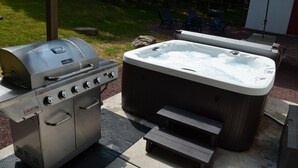 En grill och ett utomhusbubbelbadkar är uppställda.