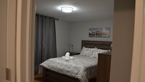Ett sovrum med en säng, ett nattduksbord, en lampa och en vägg med två tavlor.