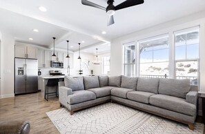 A modern kitchen with a stainless steel refrigerator, a bar area, and a grey sectional sofa. - *NEW* Comfy 4 bdrm close to resorts, trails, lakes (kamas)